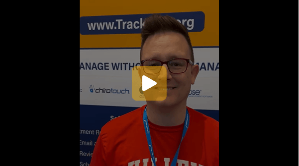 Video thumbnail: man with glasses in a red shirt and blue lanyard at a booth, banner with a website URL behind him