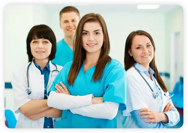 Healthcare team of four smiling clinicians posing together in a clinic setting.